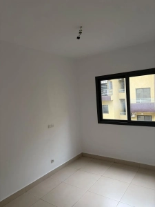 Chambre lumineuse de l'appartement 4 pièces à louer à Attécoubé, Cité ADDOHA avec fenêtre et carrelage clair