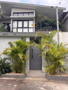 Vue extérieure de la villa à louer à Bingerville, façade à étage et jardin de palmiers