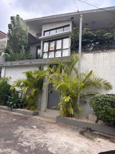 Façade de la villa à louer à Bingerville avec portail gris et palmiers