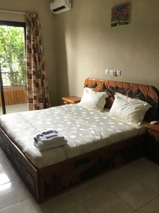 Chambre climatisée de la villa à louer à Bingerville avec lit en bois et parure blanche