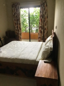 Chambre de la villa à louer à Bingerville avec lit double, rideaux et porte-fenêtre sur l'extérieur