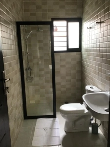 Salle d'eau de la villa à louer à Bingerville avec douche vitrée, lavabo et WC