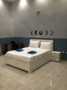 Chambre de la villa à louer à Bingerville avec lit blanc et tête de lit décorée de lunes