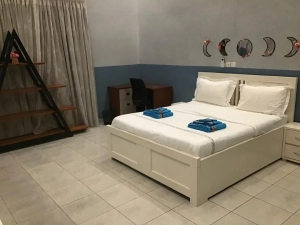Chambre de la villa à louer à Bingerville avec lit blanc et coussins turquoise