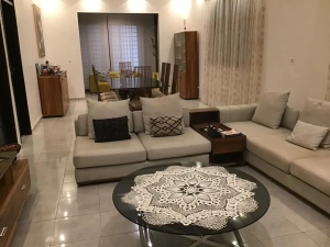 Salon spacieux de la villa à louer à Bingerville avec canapé d'angle beige et table basse en verre