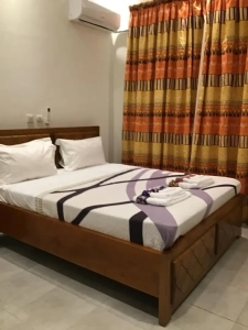 Chambre climatisée de la villa à louer à Bingerville avec lit en bois et rideaux colorés
